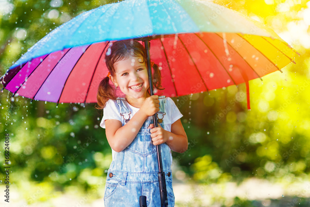 快乐的小女孩撑着伞在夏雨下嬉笑玩耍。
