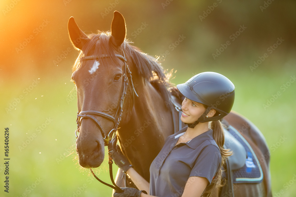 傍晚落日余晖中年轻的女骑手和她的马