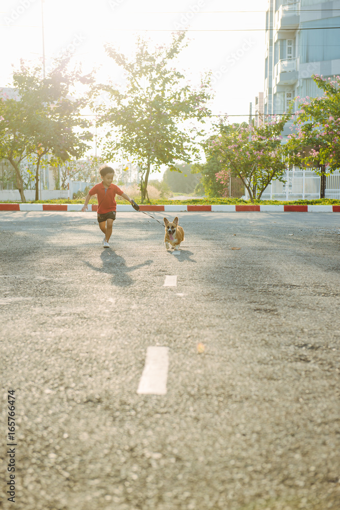 小男孩带着他的宠物狗在街上奔跑