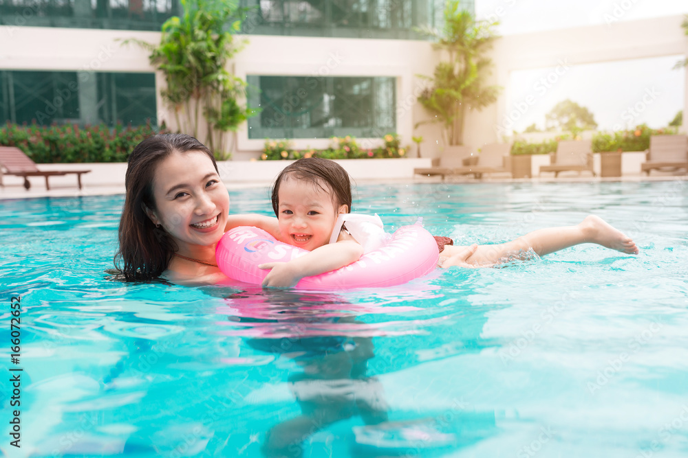 母亲和女婴在游泳池里玩得很开心。暑假和度假概念