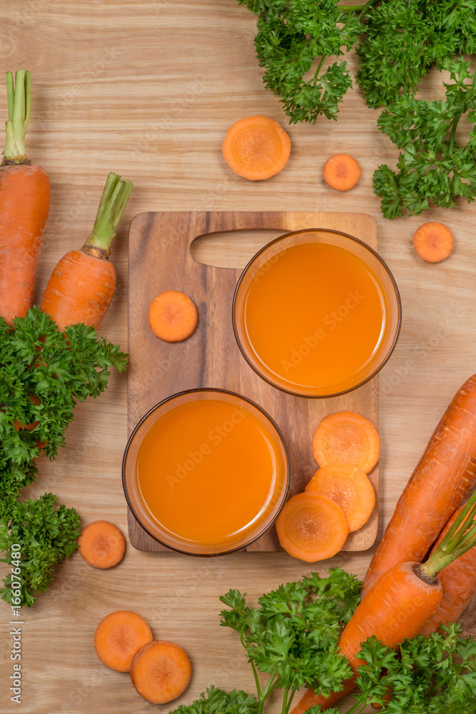 一杯新鲜的胡萝卜汁和蔬菜放在木桌上。