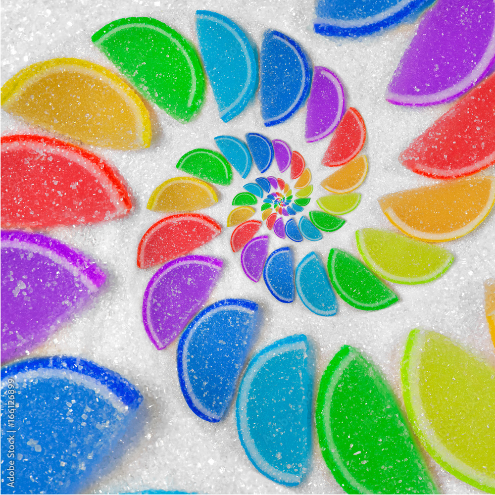 抽象的螺旋状水果果冻彩虹楔形切片，背景是白糖沙。彩虹果冻可以