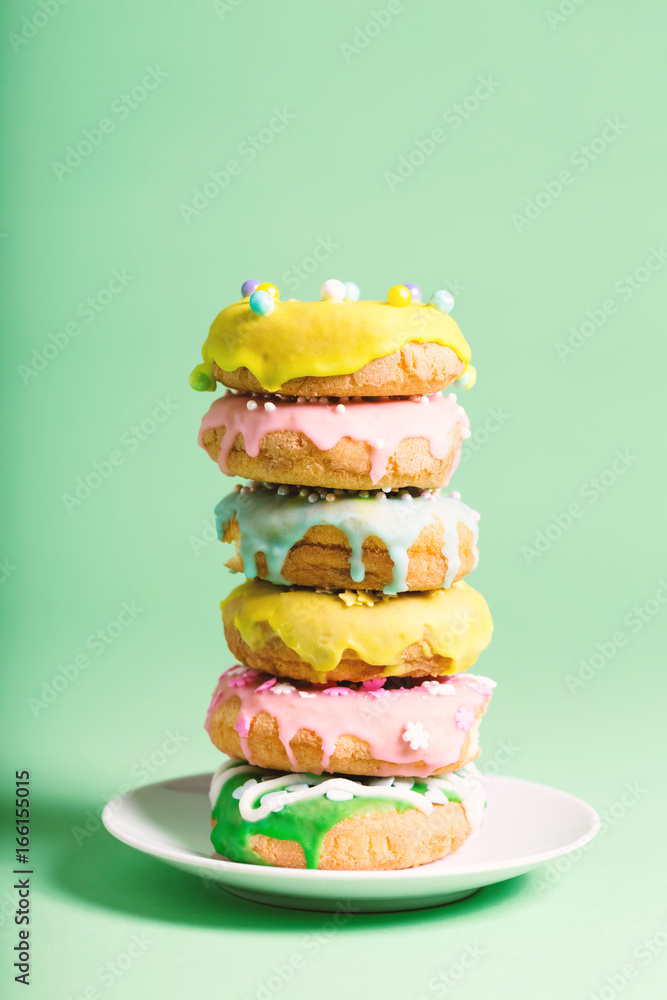 Colorful glazed donuts on a bright green background