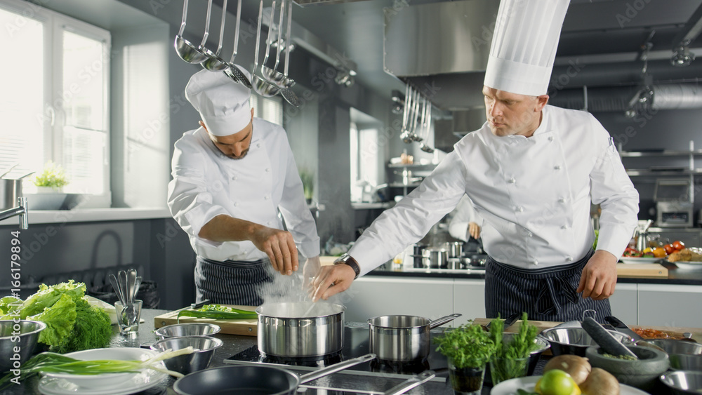 两位著名厨师在一家大餐厅的厨房里团队工作。蔬菜和配料无处不在