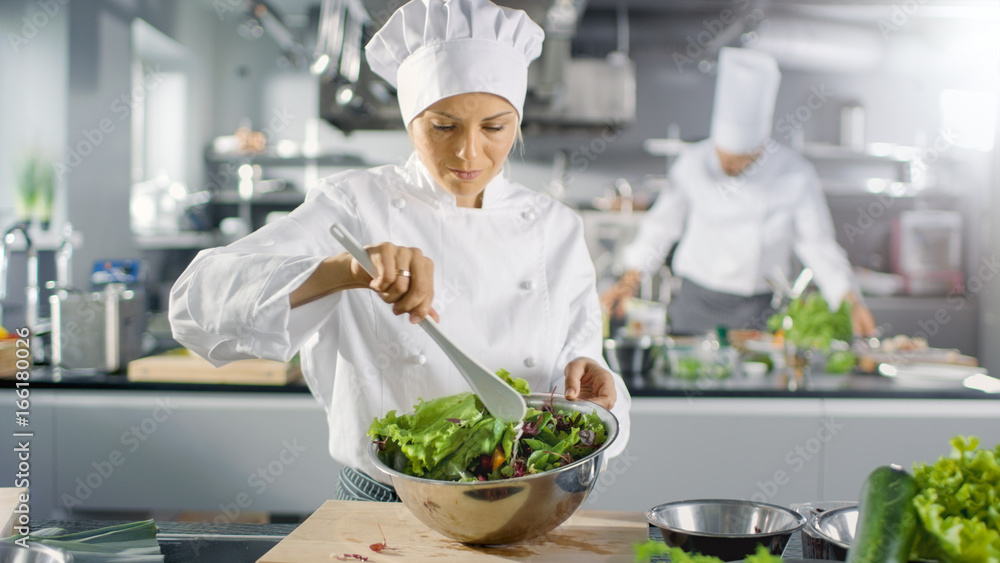 在一家著名的餐厅里，女厨师准备沙拉。她在一家现代化的大厨房工作。