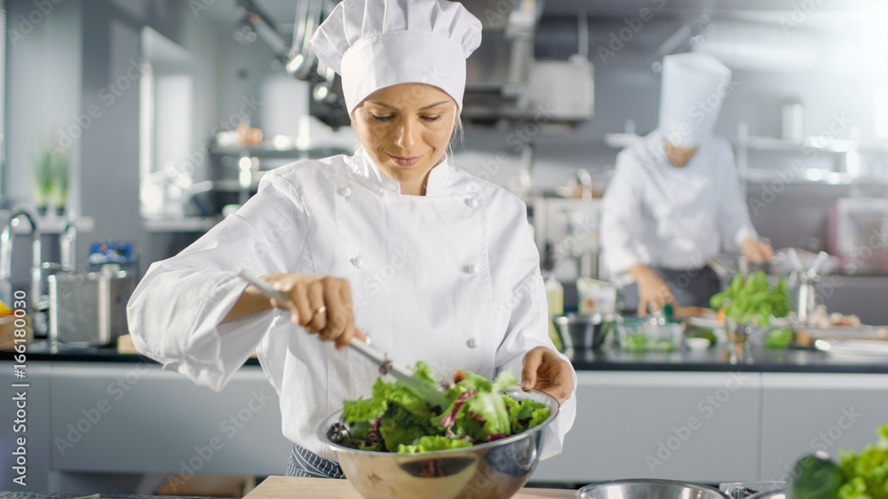 在一家著名的餐厅里，女厨师准备沙拉。她在一家现代化的大厨房工作。