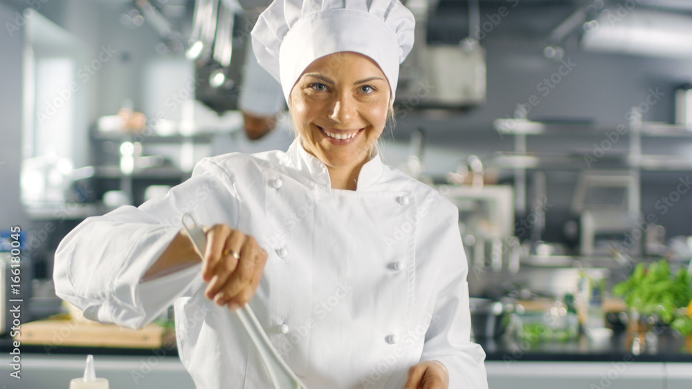 在一家著名的餐厅里，女厨师准备沙拉，对着镜头微笑。她在一家大型现代餐厅工作