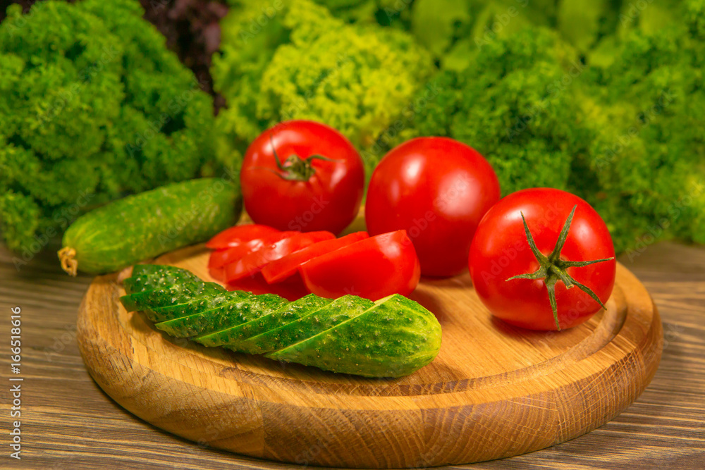 新鲜蔬菜。木桌上的西红柿和黄瓜。背景是绿色沙拉。