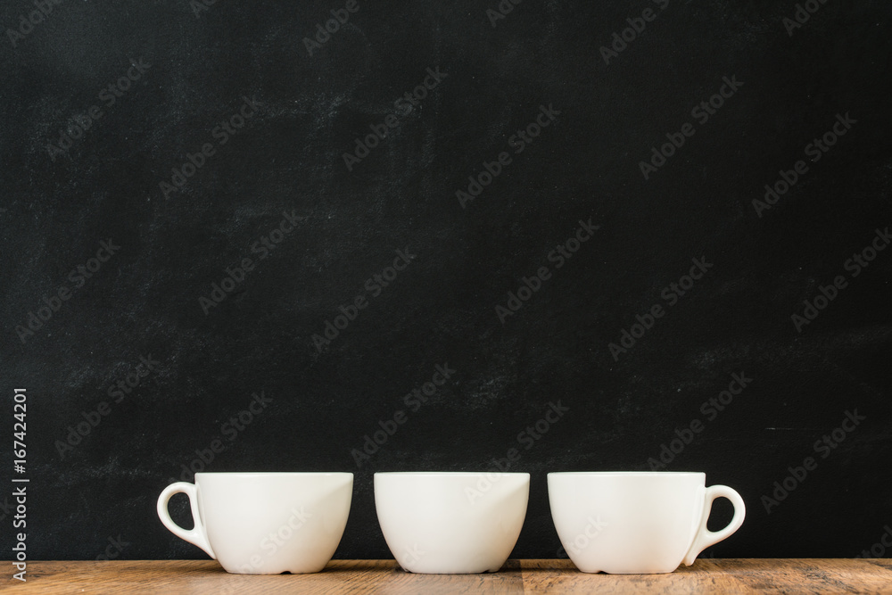 三个白色咖啡杯排列在一起，放在复古木质地板上，黑色黑板w
