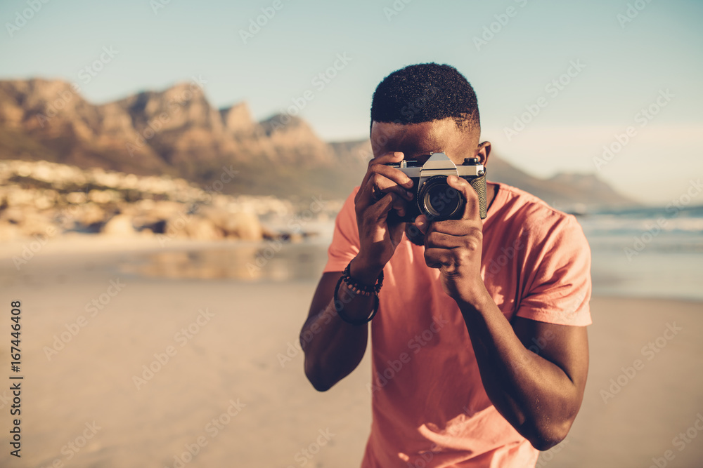 黑人在海滩上使用数码相机