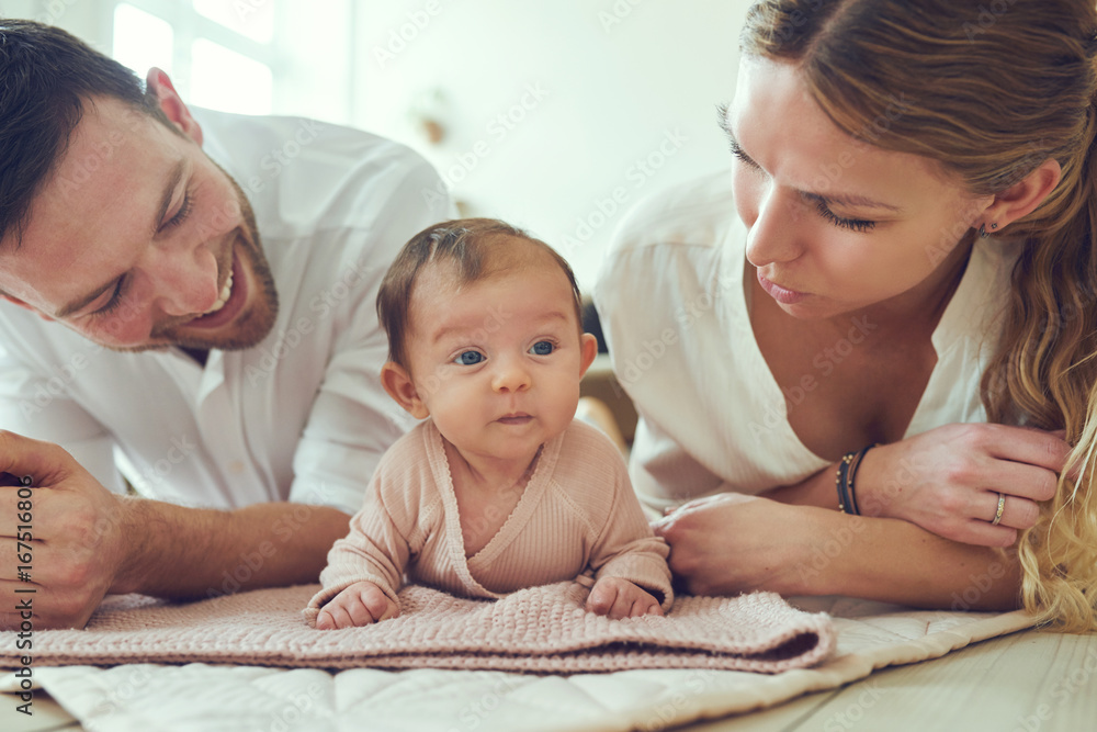 微笑的年轻父母和他们的女婴躺在家里