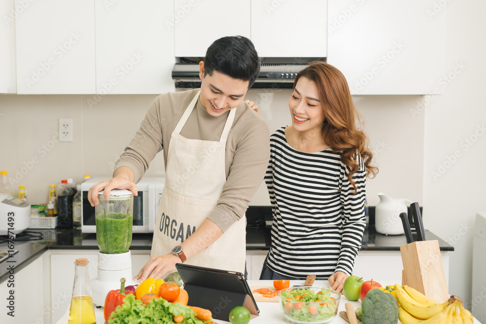 Portrait of happy asian young couple cooking together in the kitchen at home.