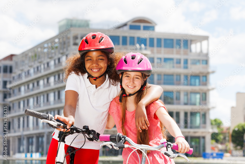夏日城市骑自行车的两个快乐女孩