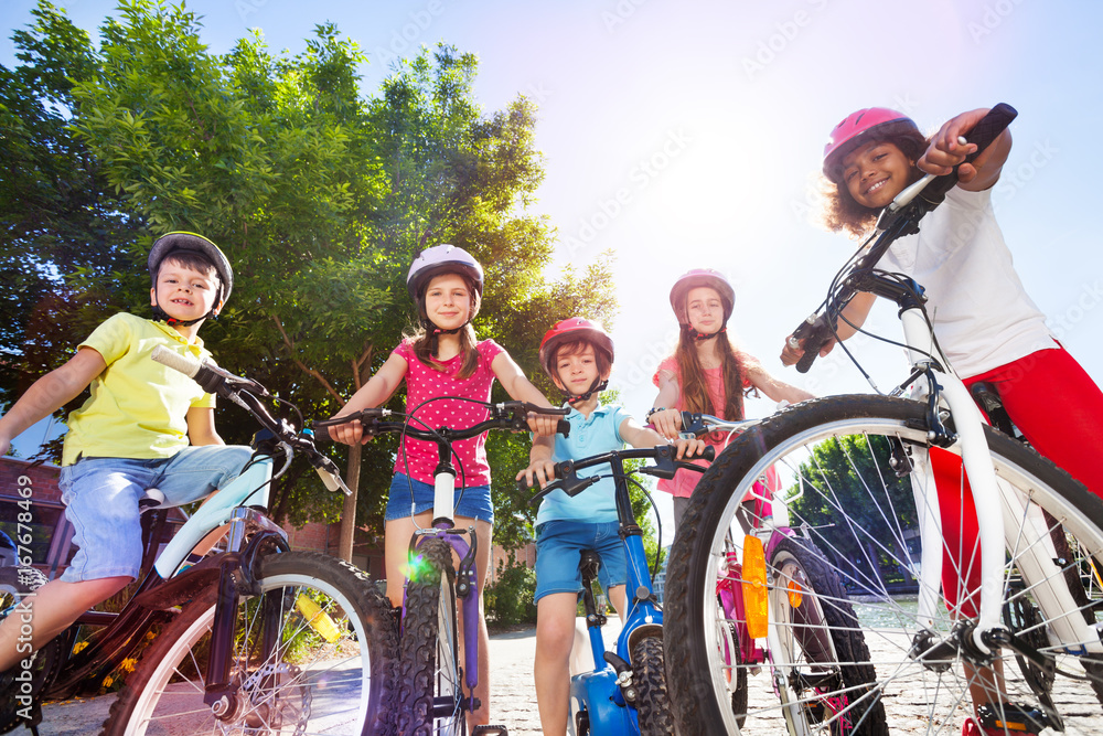 快乐的孩子们在夏季公园骑自行车