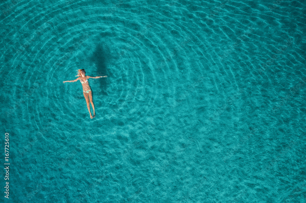 蓝色泻湖中游泳女子的鸟瞰图。土耳其奥卢代尼兹的地中海。夏季海景
