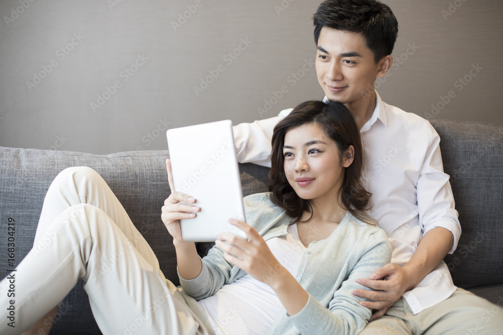 快乐的年轻夫妇在家使用数字平板电脑