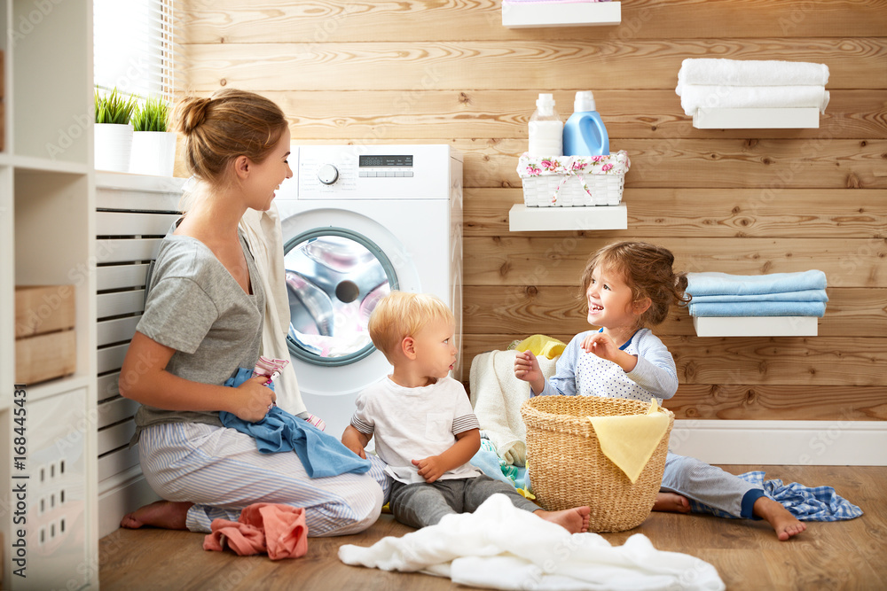 快乐家庭母亲家庭主妇和孩子在洗衣机里洗衣