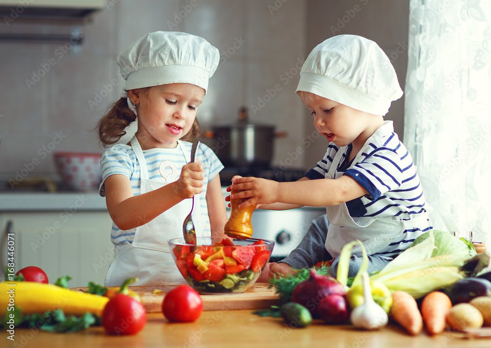 Healthy eating. Happy children prepares  vegetable salad in kitchen