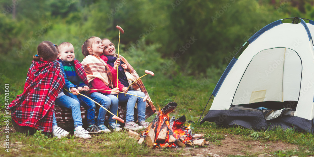 孩子们在帐篷附近的木桩上笑着炸香肠