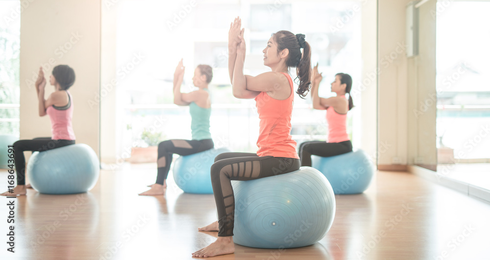 健身、运动、训练、瑜伽和人的概念——亚洲女性在健身房的瑜伽球上伸展身体。小组