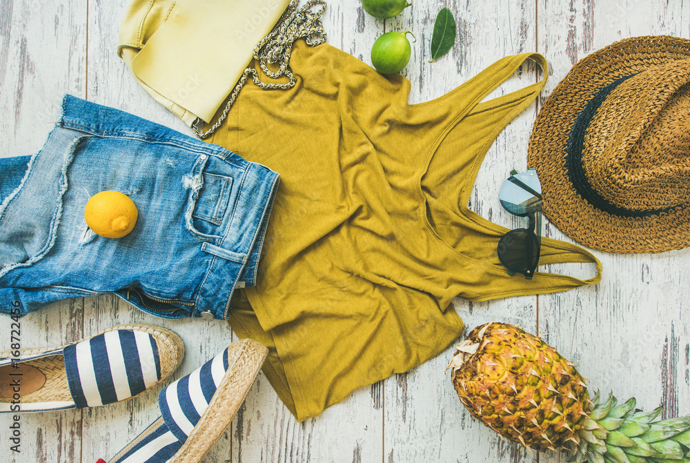 Colorful summer fashion outfit flat-lay. Denim shorts, straw sun hat, yellow top, espadrillas, leath