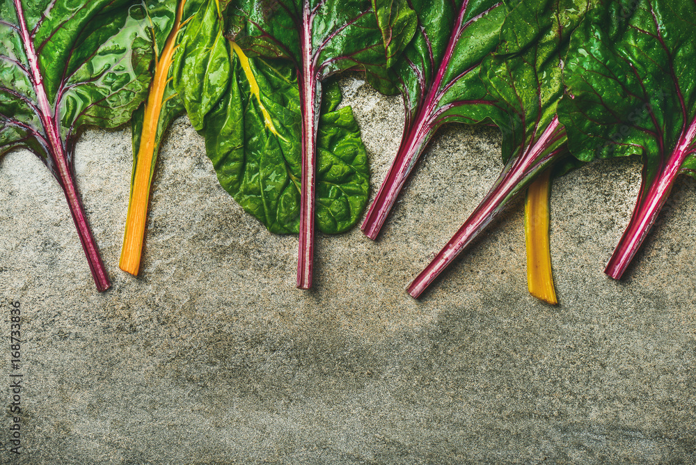 Flat-lay of fresh colorful leaves of swiss chard over concrete stone background, copy space, top vie