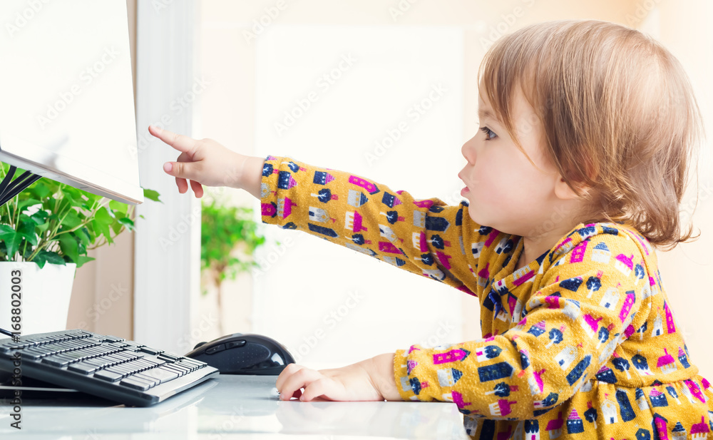 蹒跚学步的女孩指着她的电脑屏幕