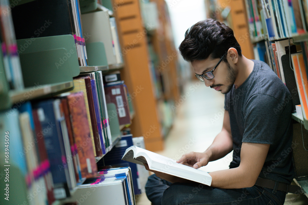 图书馆书架上的亚洲学生。她正在读书