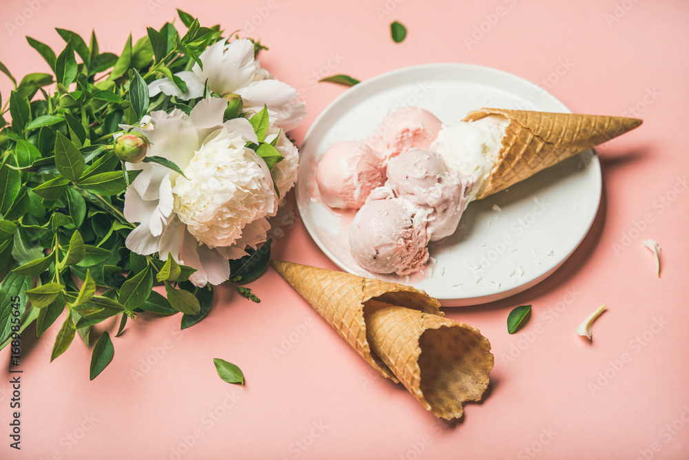 淡粉色草莓和椰子冰淇淋勺、白色盘子上的甜甜筒和白色冰淇淋