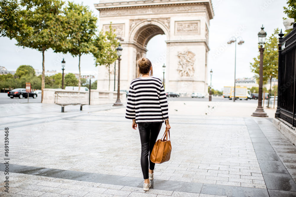 Lifestyle portrait of a young stylish business woman walking outdoors near the famous triumphal arch