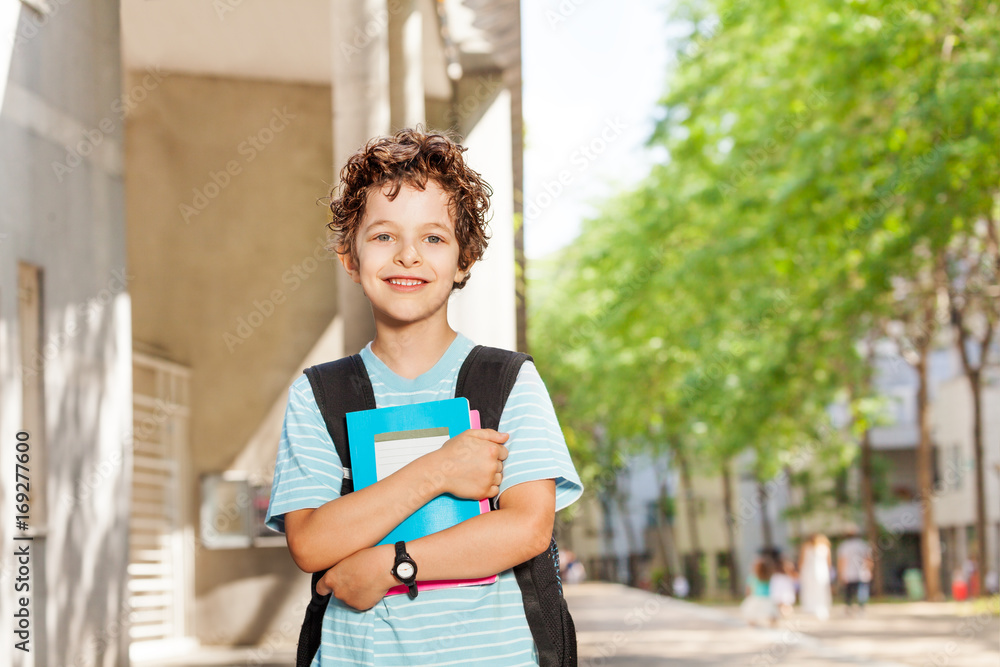 Portrait of handsome boy with books near school