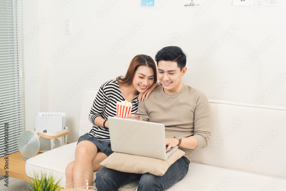 Young asian couple payment online using laptop buying movie ticket