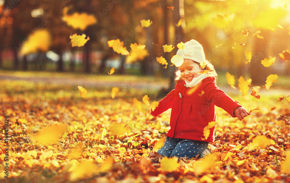 快乐的小女孩扔秋叶开怀大笑