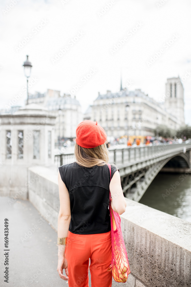 巴黎街头，一位戴着红色帽子、背着装满法国食物的网袋的年轻时尚女士