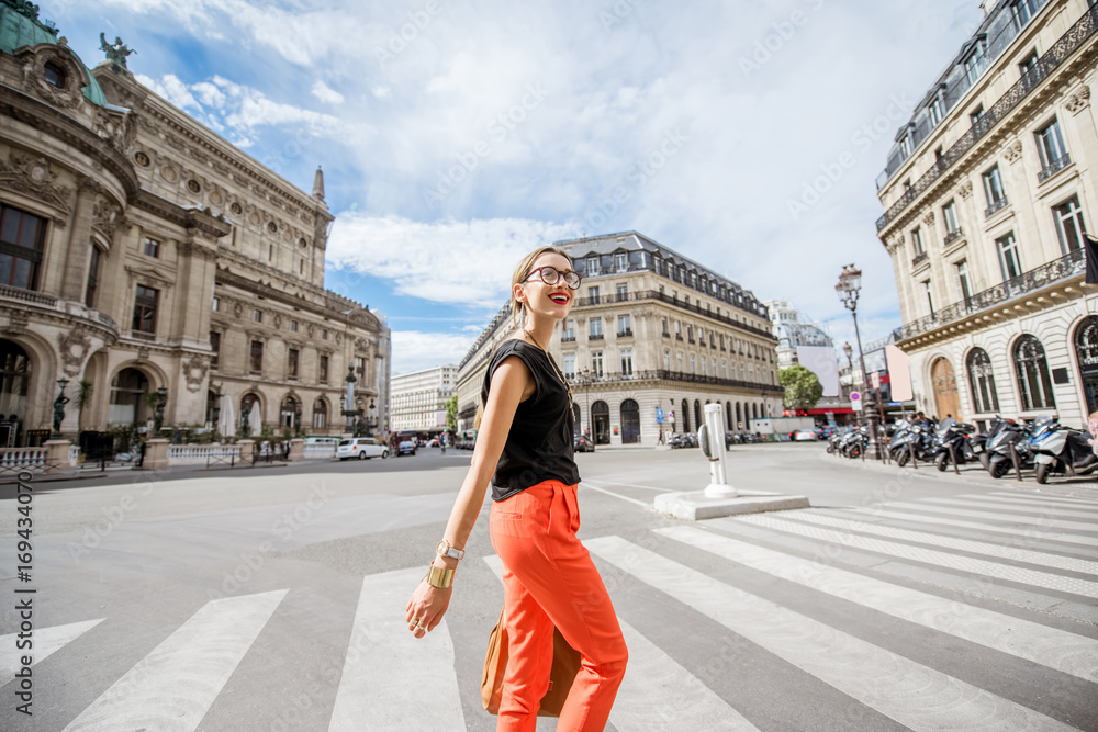 穿着红色裤子的年轻时尚女人在巴黎过马路