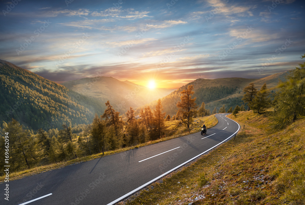 摩托车司机在阿尔卑斯山高速公路上骑行。户外摄影，山地景观。
