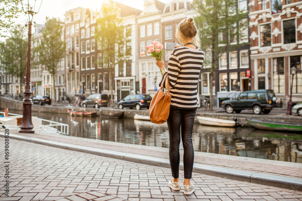 阿姆斯特丹水道附近，一位女士拿着一束粉色郁金香散步的生活方式肖像