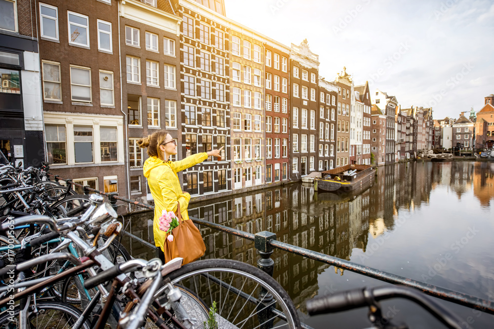 身穿黄色雨衣的年轻女子在阿姆斯特丹欣赏美丽的城市景观