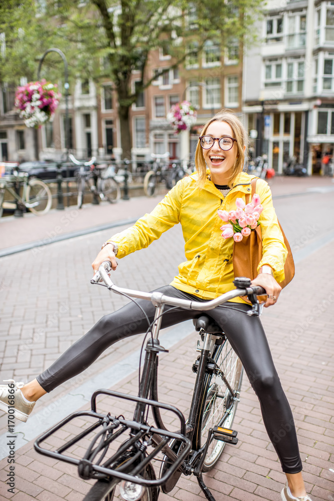 穿着黄色雨衣的年轻女子在阿姆斯特丹骑自行车玩得很开心