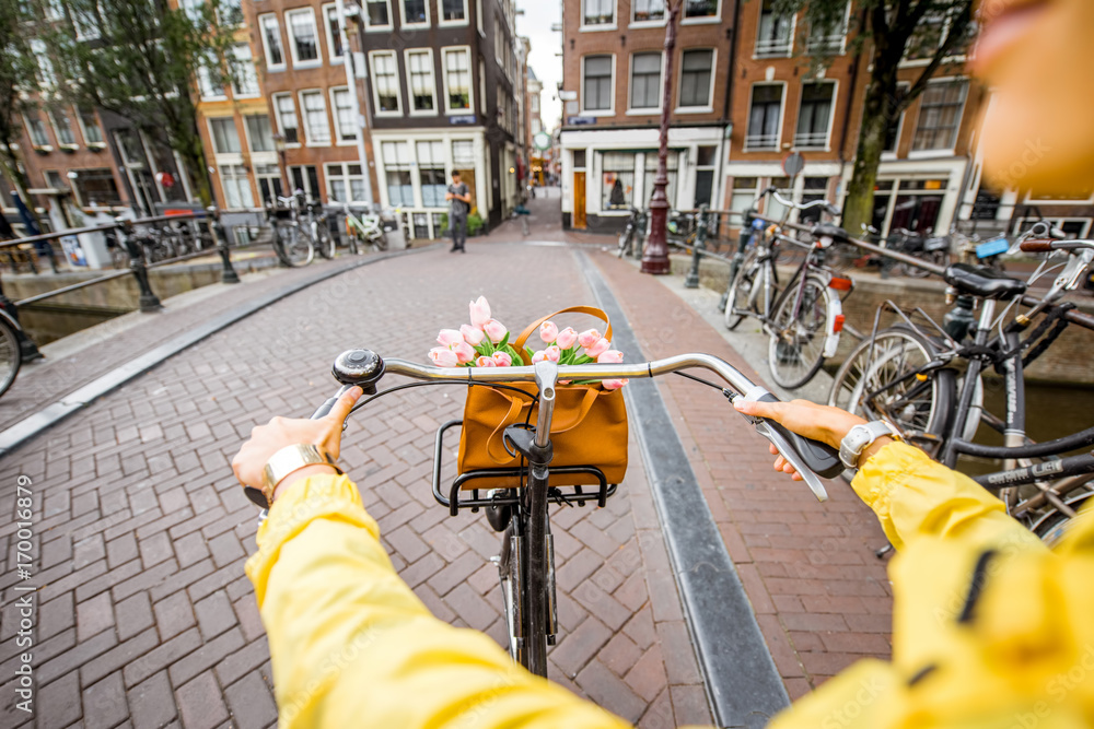 阿姆斯特丹街头，一名妇女骑着自行车，手里拿着一束鲜花。在手上观看ho