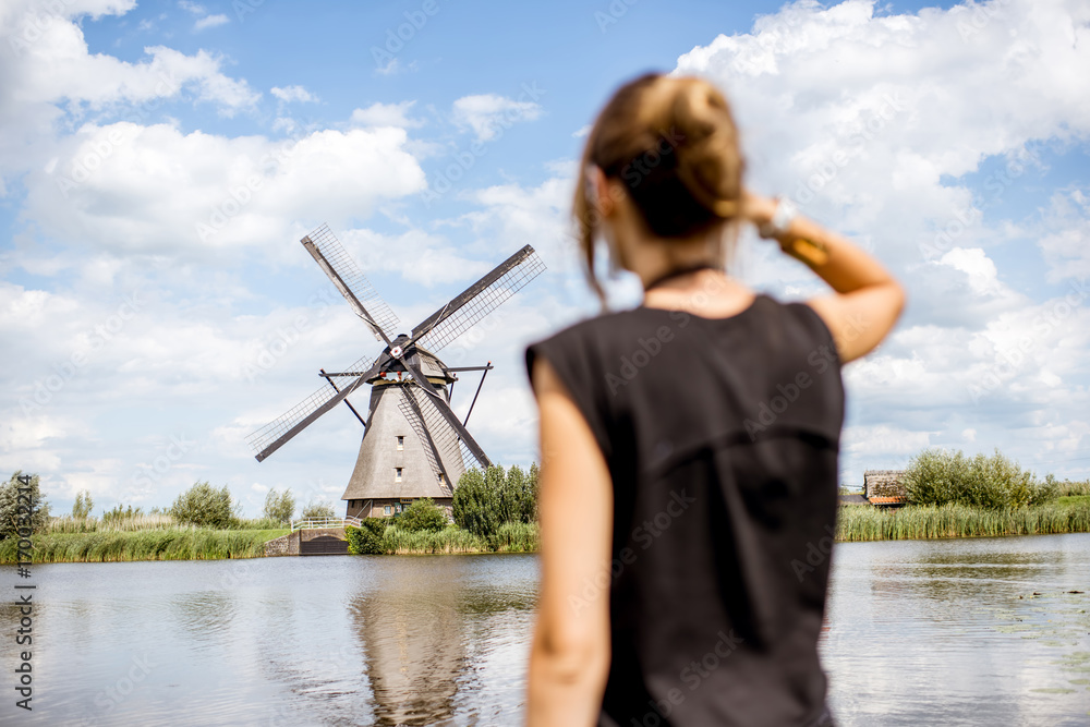 年轻女子在荷兰欣赏古老风车的美景。女人走神了