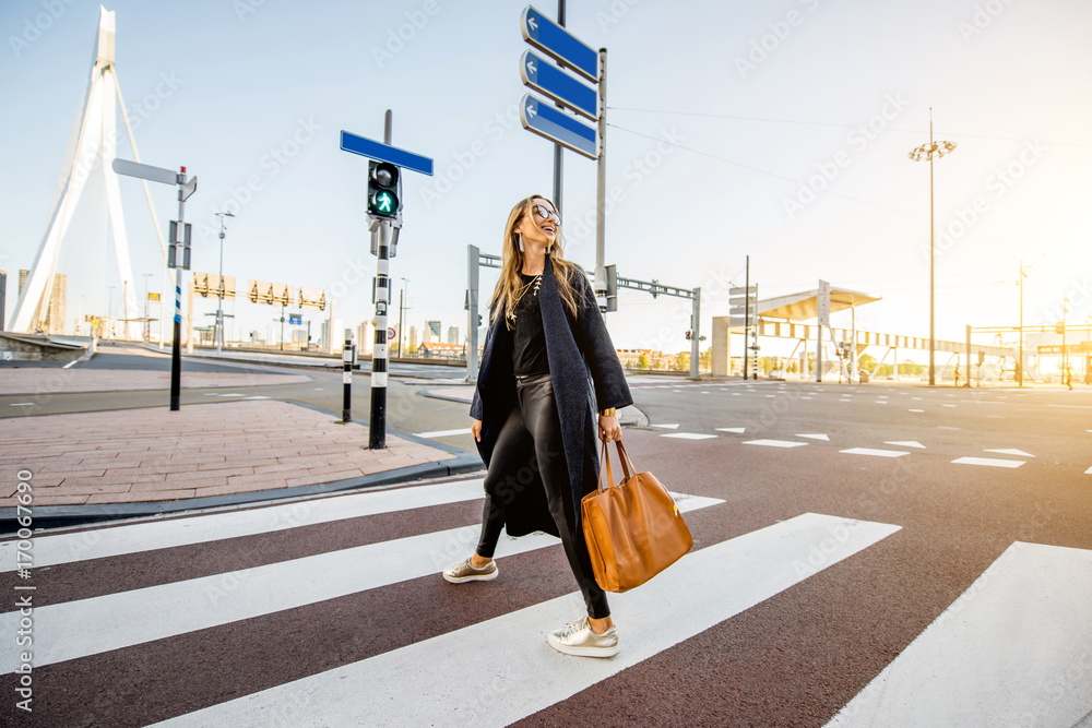 时尚的女商人在鹿特丹市的现代街区穿过街道
