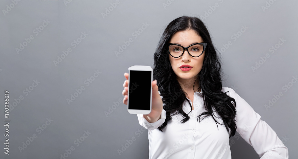 Young woman holding out a cellphone in her hand
