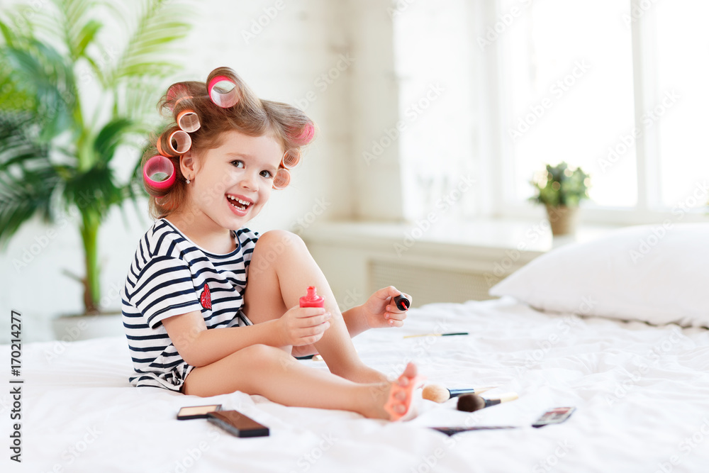 快乐有趣的带卷发器的小女孩修脚、涂指甲、大笑