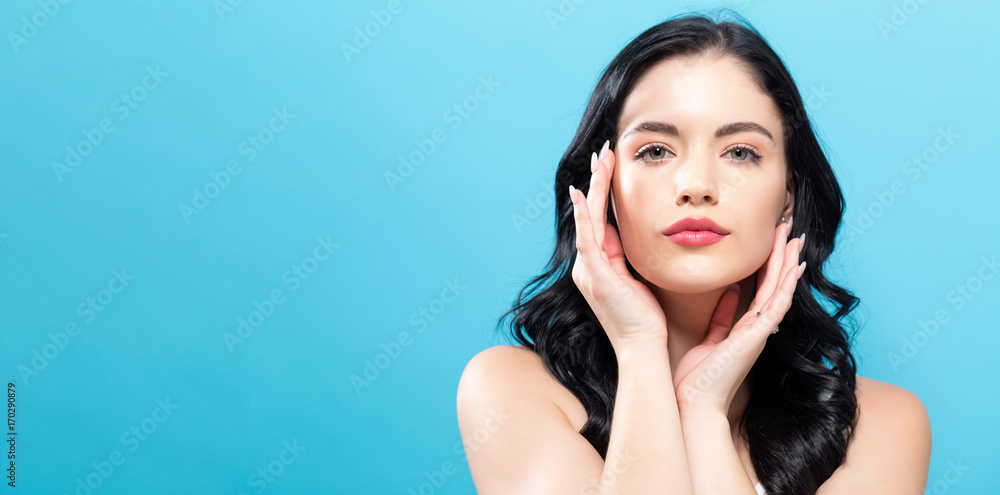  Beautiful young woman touching her face in skin care theme