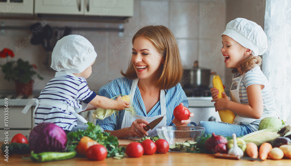健康饮食。快乐家庭母亲和孩子们在厨房准备蔬菜沙拉。