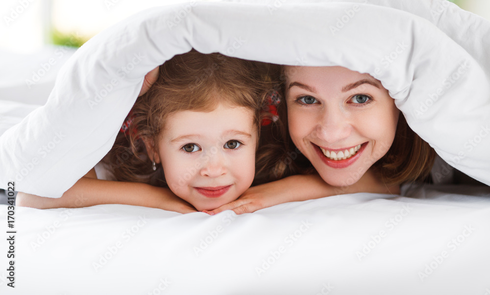 幸福的家庭母亲和孩子女儿在床上大笑