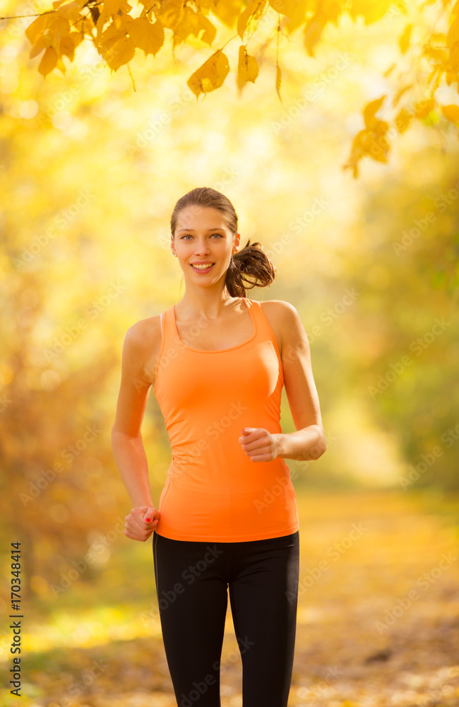 Young brunette woman running in autumn forest