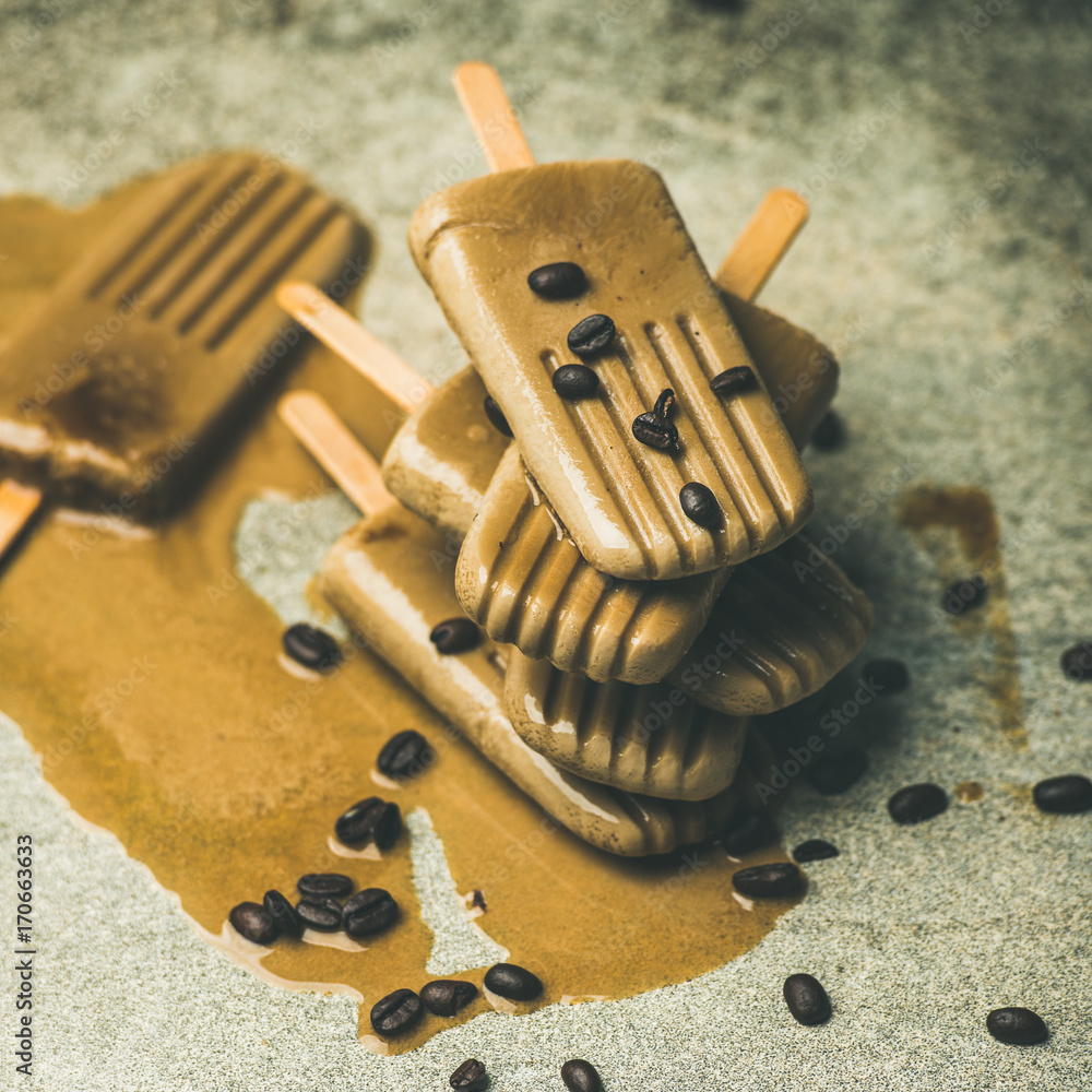 Summer healthy vegan frozen dessert. Flatlay of melting coffee latte popsicles with coffee beans ove