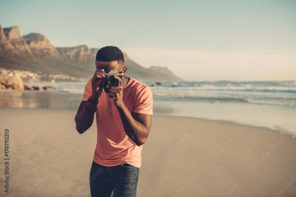 男子在海滩用数码相机拍照